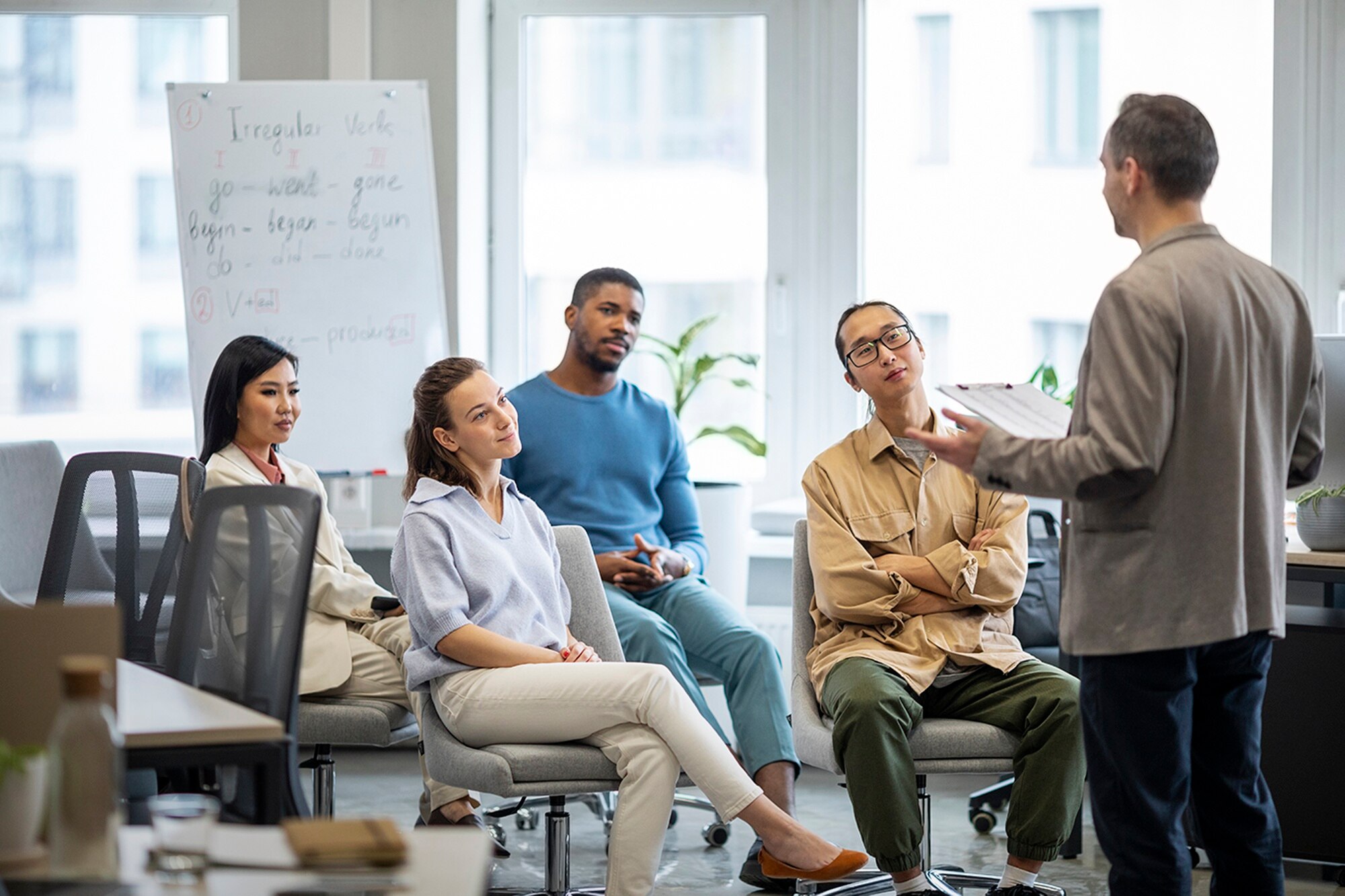 A diverse group of four professionals engages in conversation in a modern office setting, promoting collaboration and discussion.